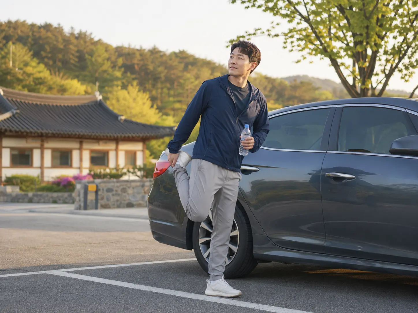 장시간 운전 후 주차된 차량 옆에서 다리를 가볍게 풀고 쉬는 성인 남성