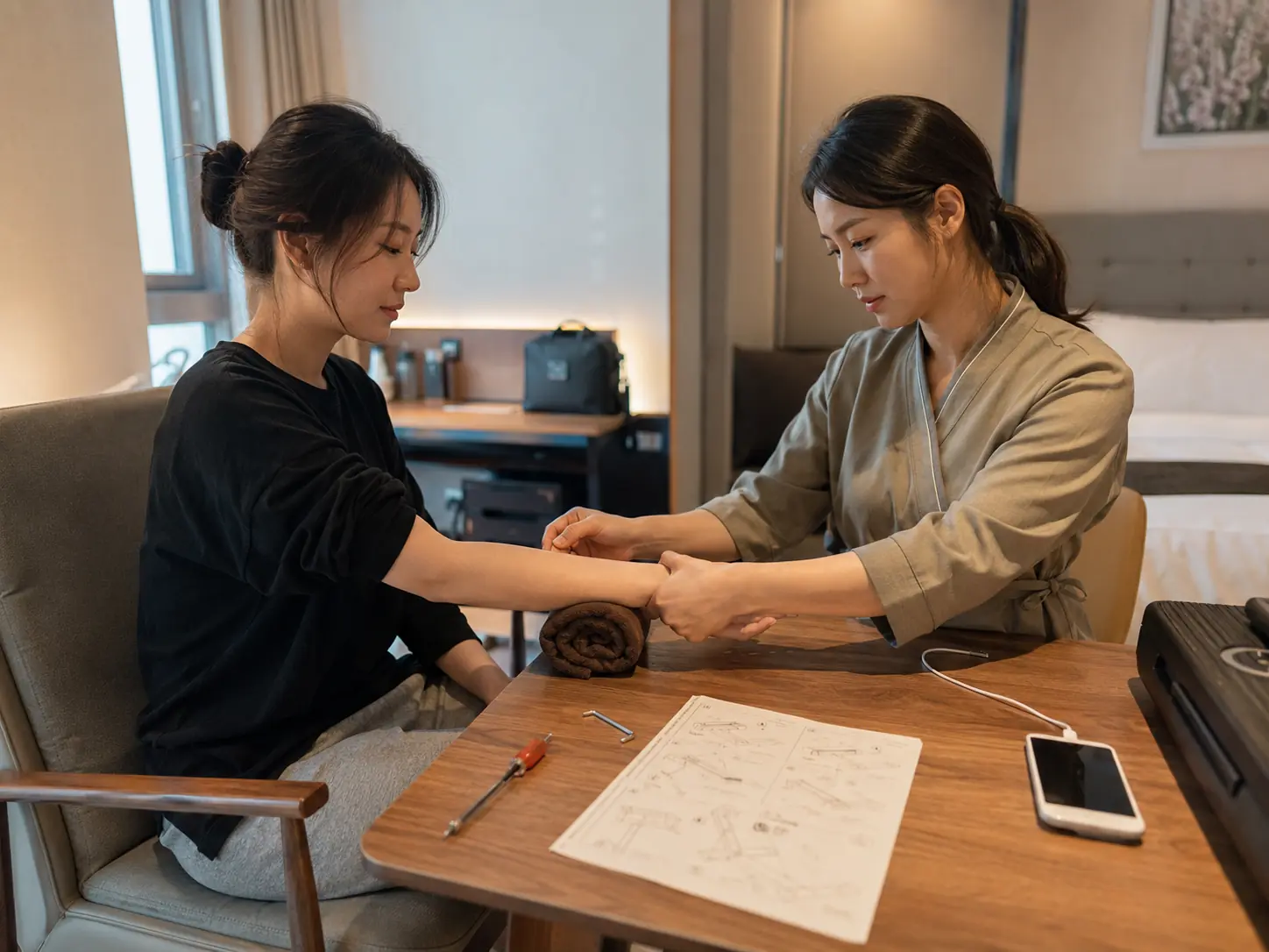 충북 진천 덕산읍 숙소에서 젊은 성인 여성 관리사가 로컬 에디터 지우의 손목을 받치며 팔을 부드럽게 관리하는 장면